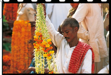 Flower seller at Varanasi with handmade garland of Jasime and marigold flowers ti be used in a wedding ceremony