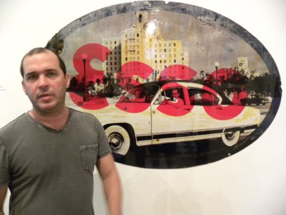 Kadir Lopez in front of his art work, original ESSO enamelled sign overlaid with photographic prints