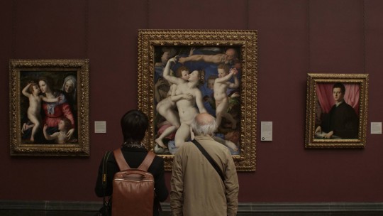 Film still: Bronzini's An Allegory with Venus and Cupid captures the attention of two visitors