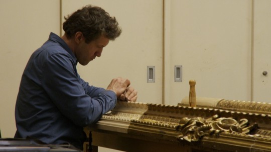 Film still. A member of the Gallery staff at work in the Framing Workshop