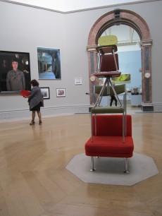 A sculpture, Work No.998 by Martin Creed in  the first room of the Summer Exhibition. On display are photographic  works, including, at left, Untitled #472 by Cindy  Sherman