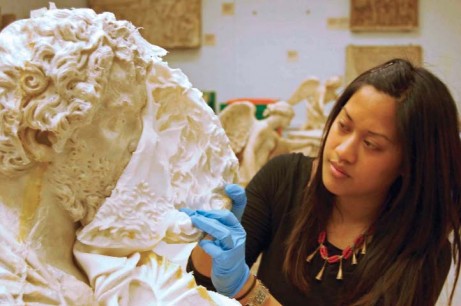 A conservator works on a sculpture