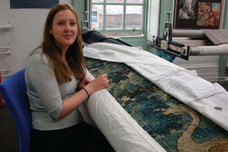 A conservator works on a tapestry