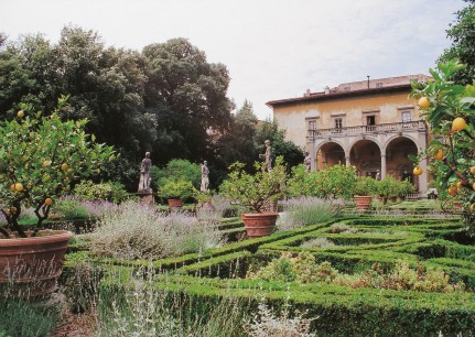 A view across a parterre, with its lemon pots and roman statues, to an arcaded seventeenth-century loggia.