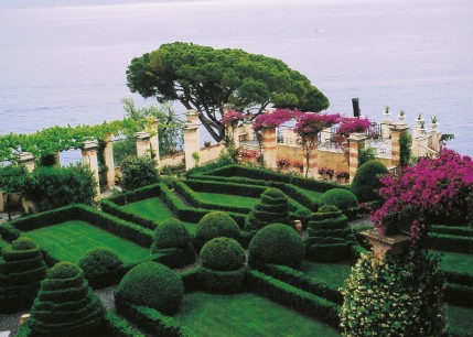 A formal parterre, laid out simply in box and grass, with pergolas overlooking the sea.